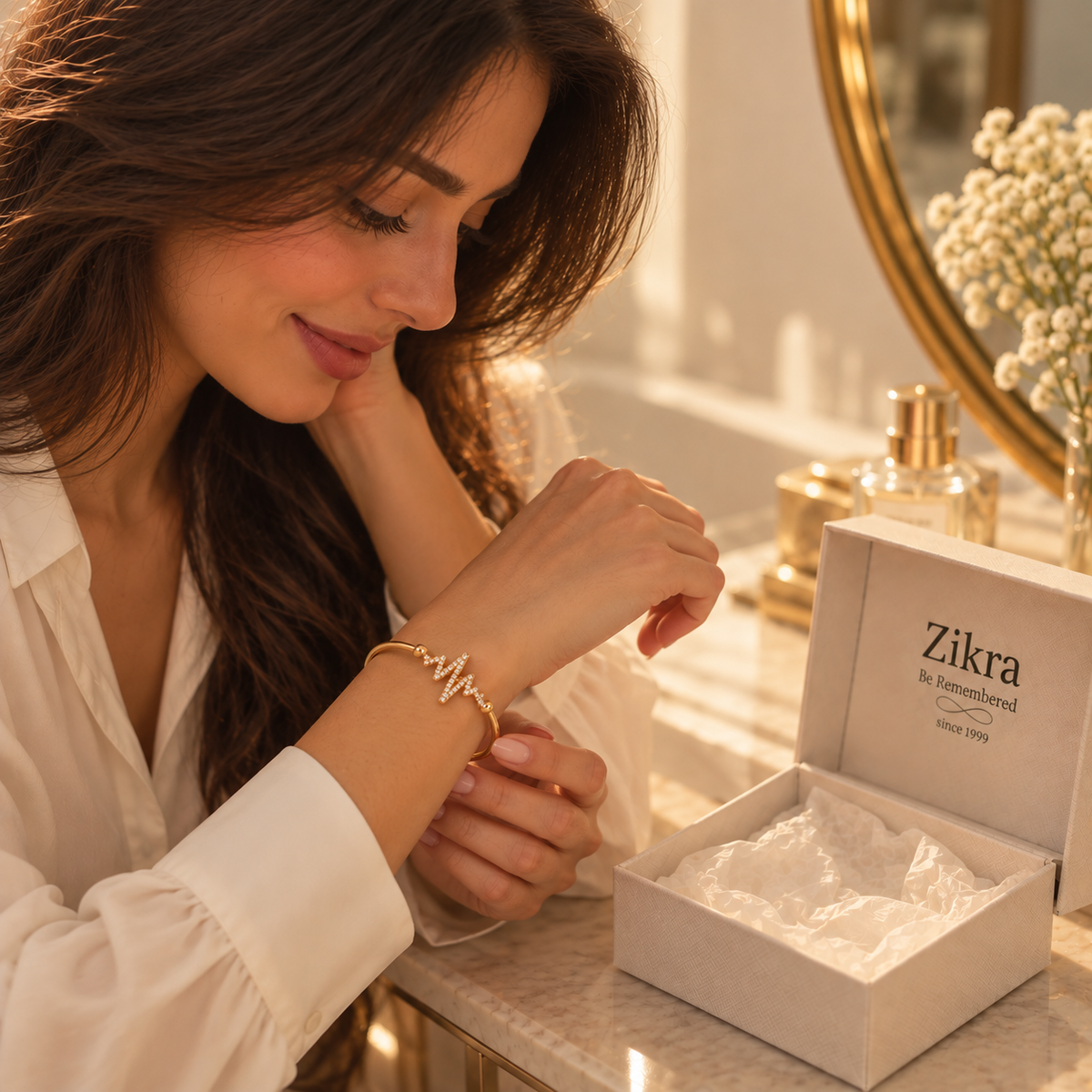 Woman wearing the Heartbeat gold bracelet beside a Zikra gift box