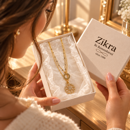 Hands holding a Zikra gift box with the Elara layered gold necklace