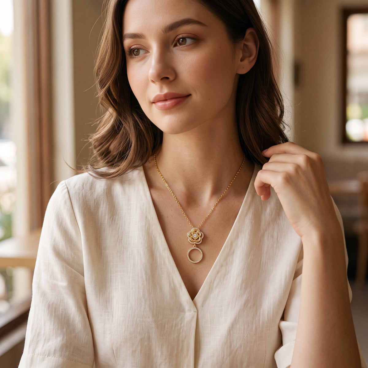 Woman wearing the Rose pendant gold necklace with a cream blouse